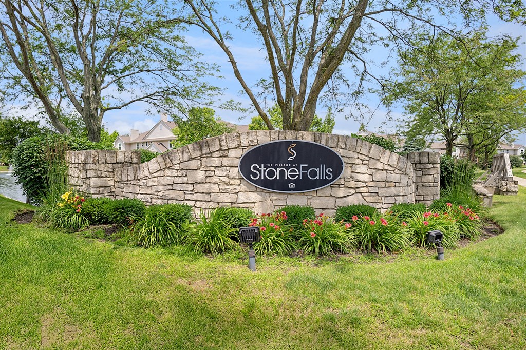 StoneFalls sign in front of a grassy area with trees.