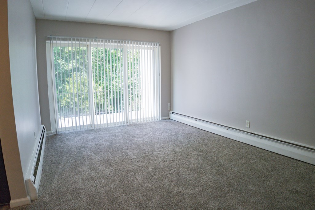 A room with a carpeted floor and a sliding glass door.