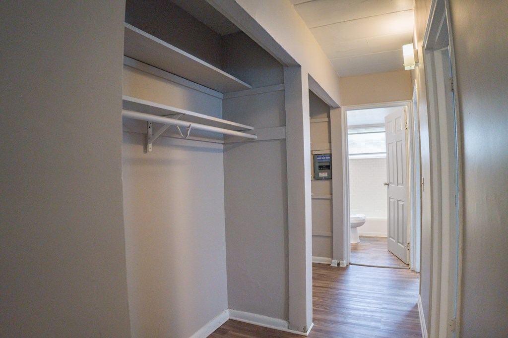 A hallway with a white door and a white wall.
