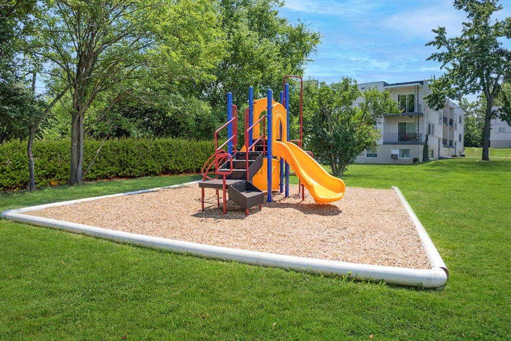 A playground with a yellow slide and a red and blue structure.