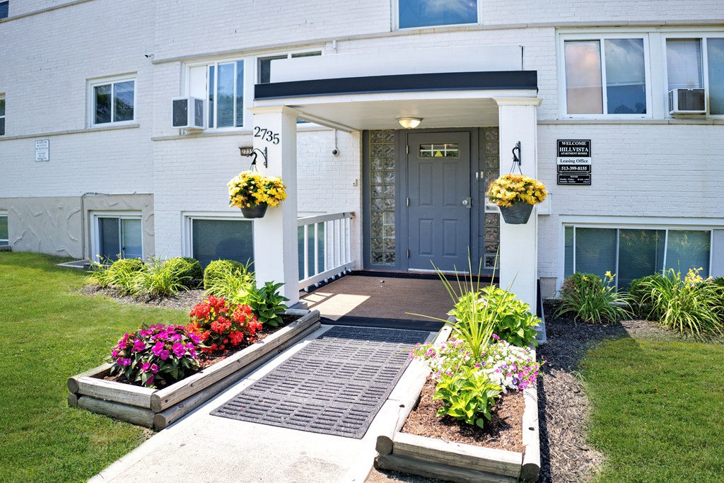 A white building with a black door and windows, and a small garden in front.