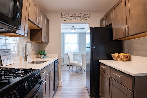 A kitchen with a black refrigerator and a sign that says "coffee caramel perfect.".