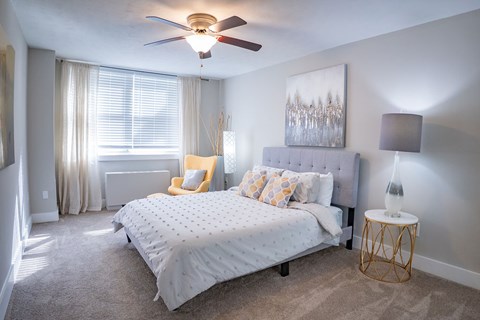 A bedroom with a bed, a chair, and a painting on the wall.