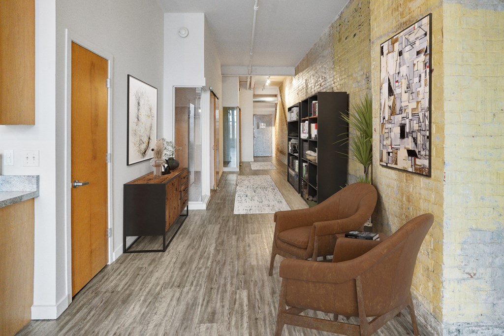 A hallway with a yellow brick wall and a long wooden flooring at The Cannery Lofts in Dayton, OH.