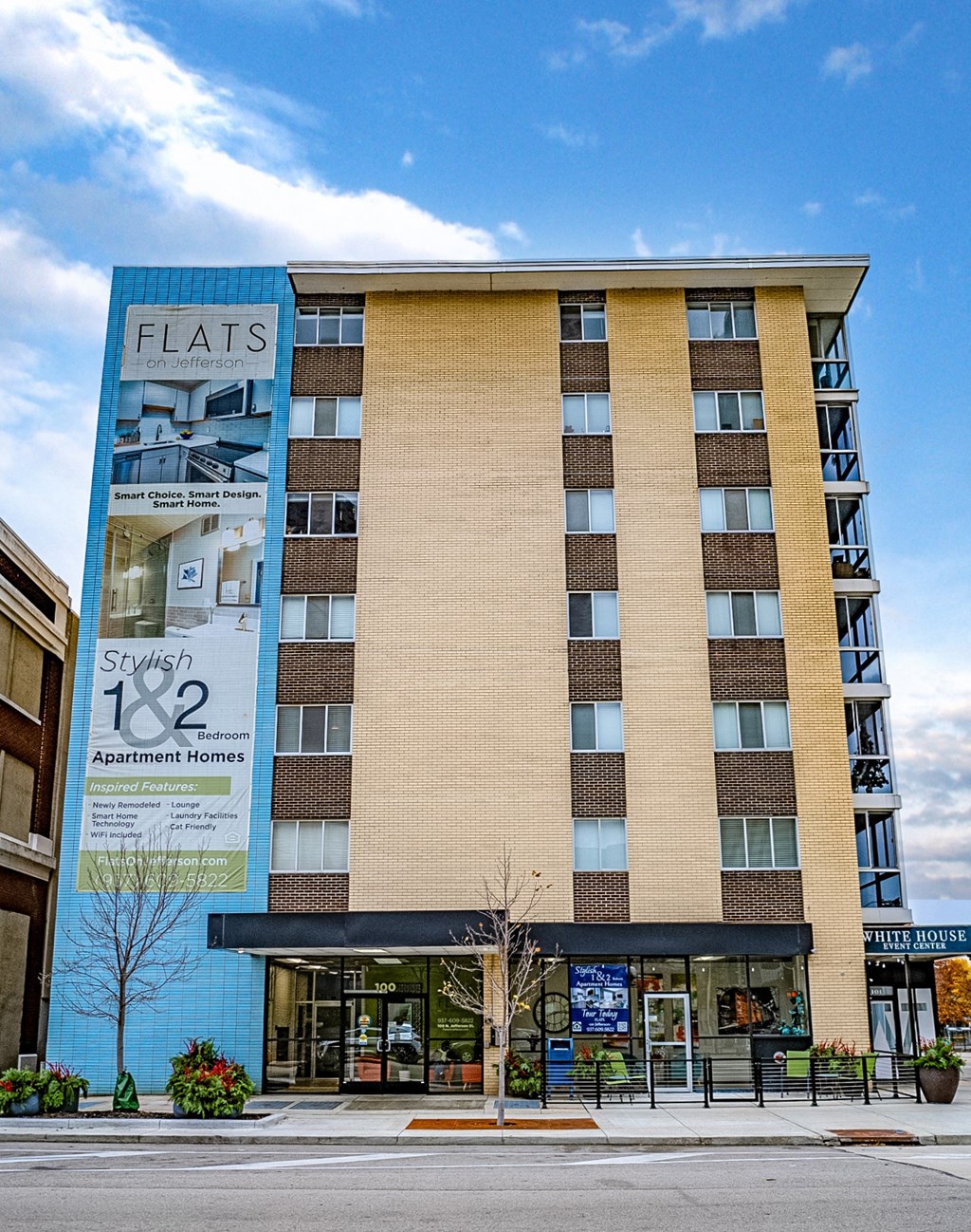 A tall building with a blue and beige facade and a sign that says Flats.