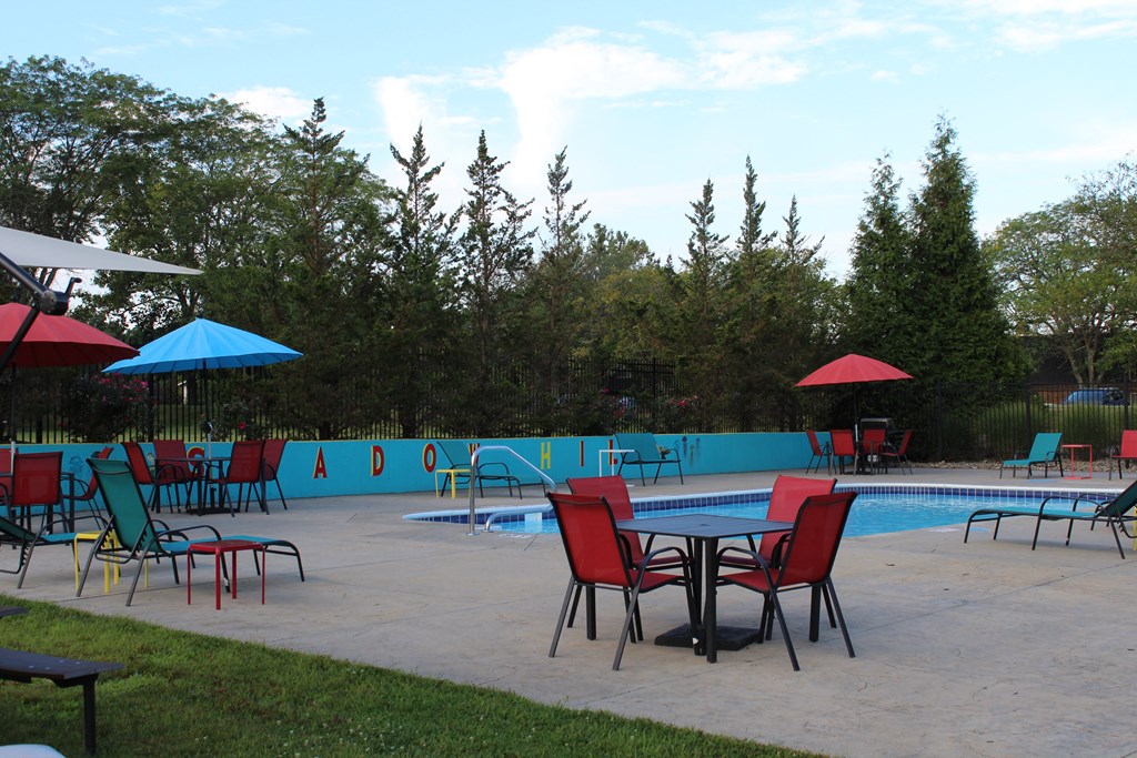 a patio with a table and chairs and a swimming pool in the background