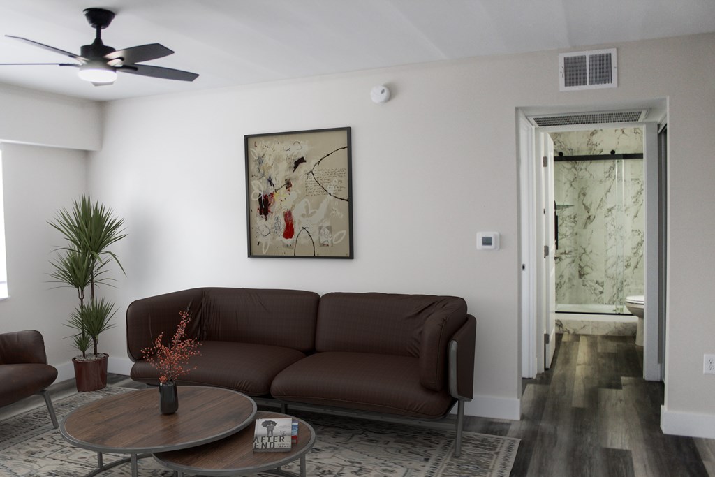 A living room with a brown sofa, a coffee table, and a painting on the wall.
