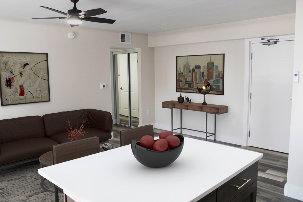 A living room with a brown couch, a white table, and a ceiling fan.