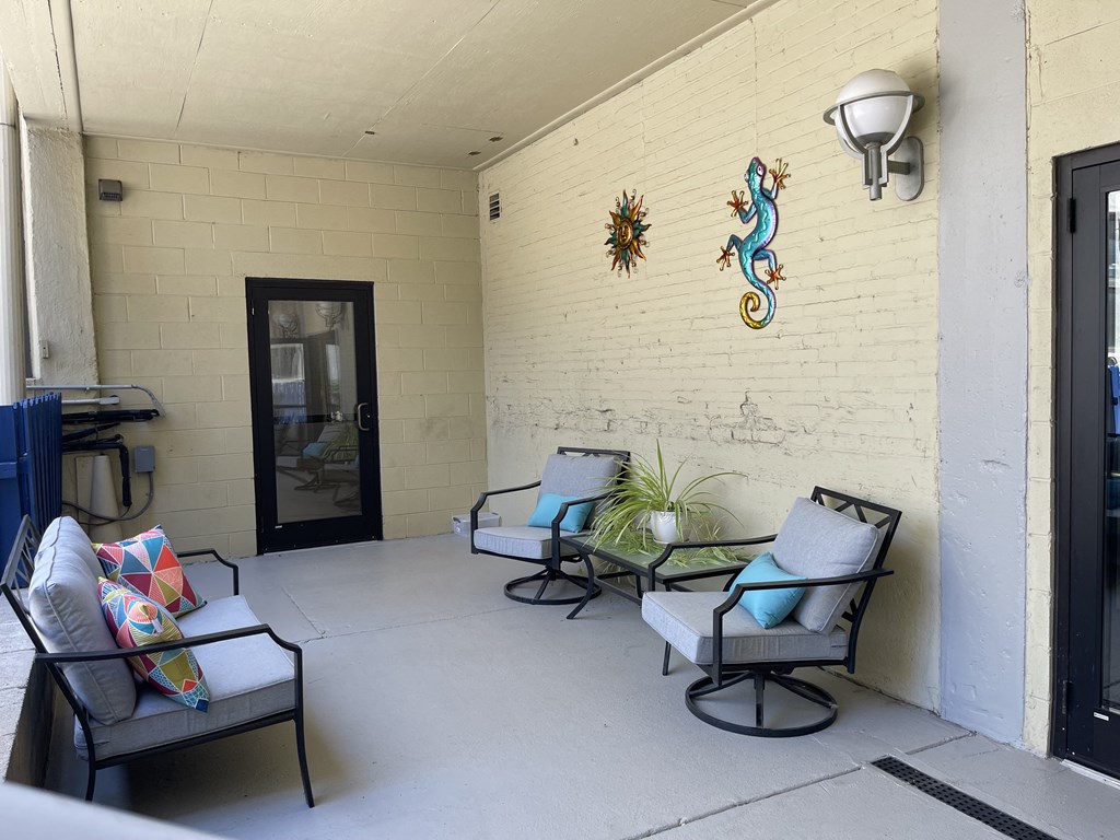 A patio with three chairs and a table with a glass door in the background a St. Clair Lofts