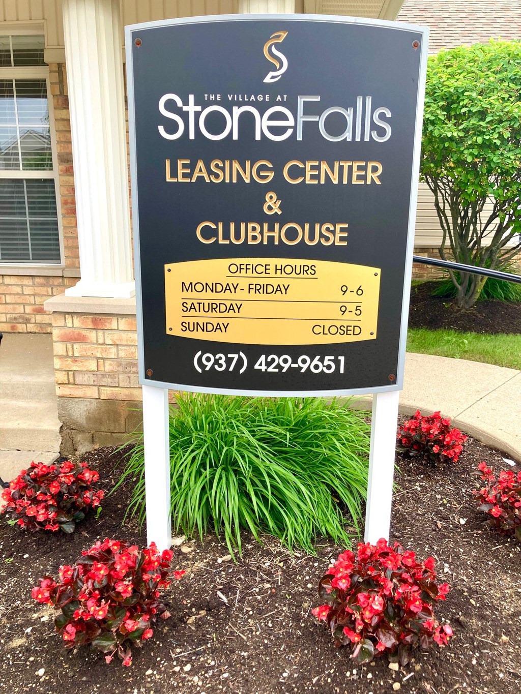 a sign for stone falls leasing center and clubhouse in front of a house