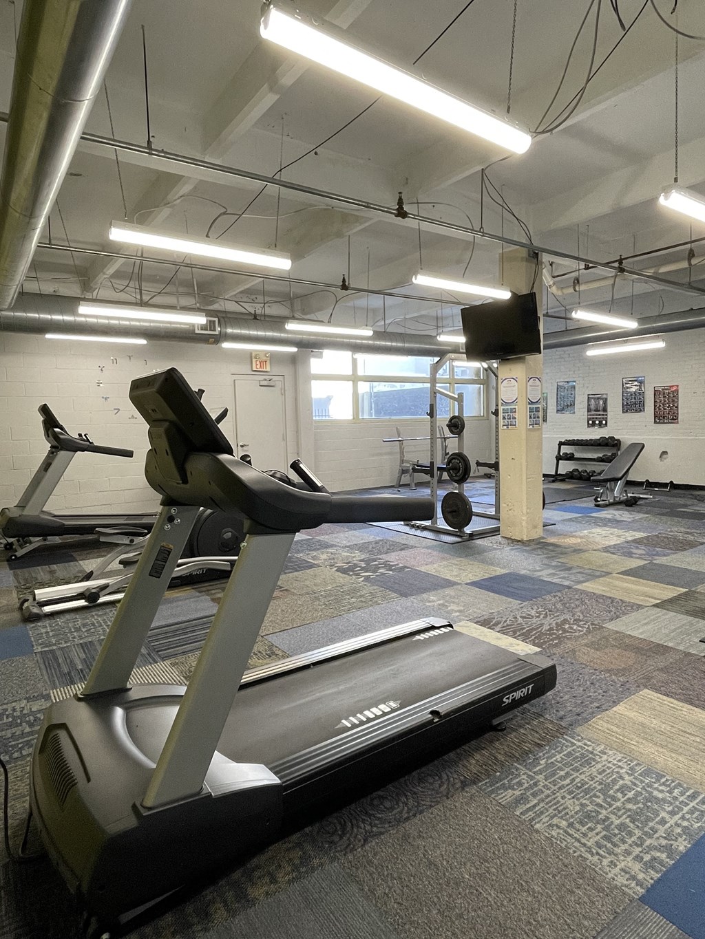 A treadmill in St. Clair Lofts fitness center with bright overhead lighting
