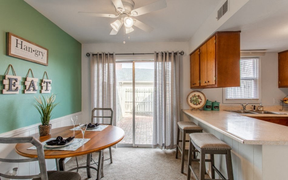 Model unit dining area with a table and chairs next to a kitchen with a sliding glass door