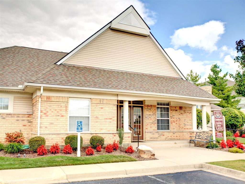 the front of a brick house with a porch and a sign