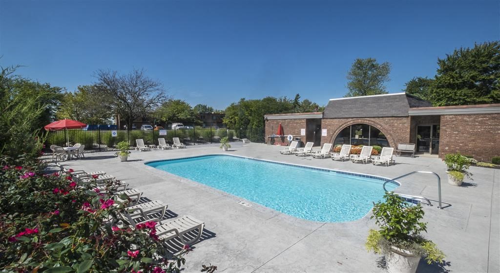 a swimming pool with chairs and a brick building