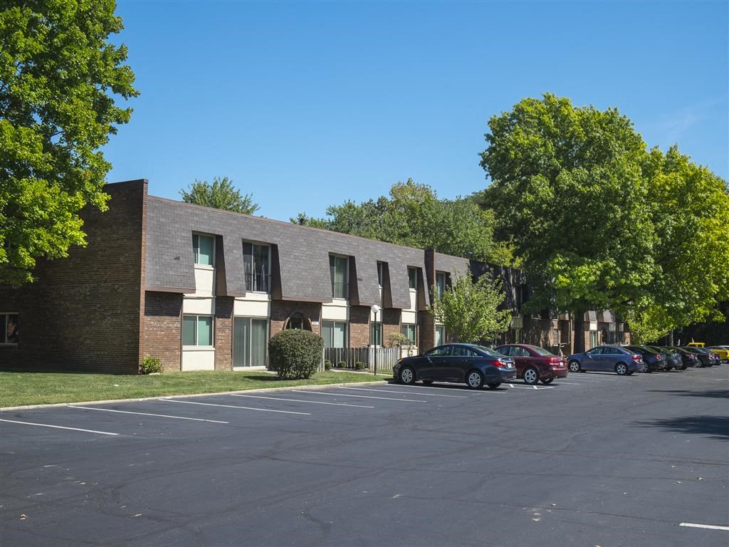 an apartment building with cars parked in a parking lot