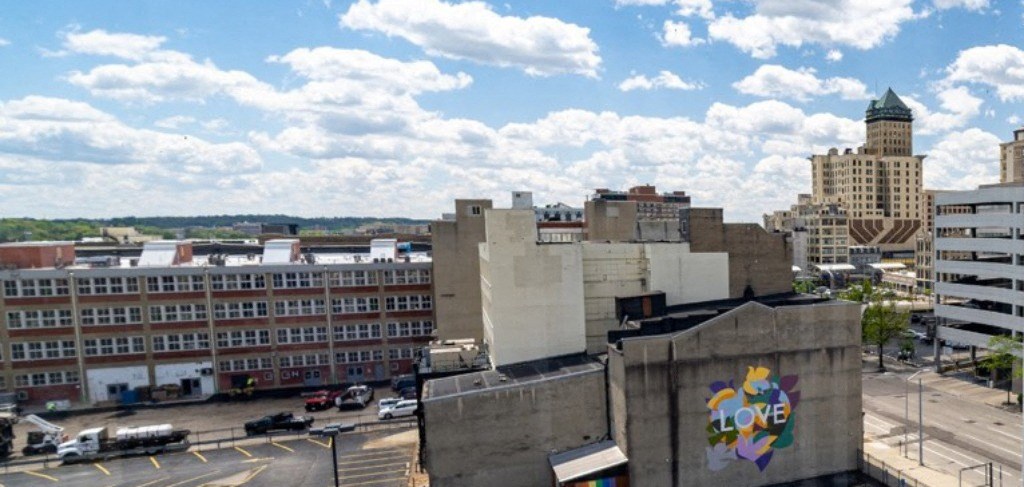 A cityscape with a large building in the foreground and a cloudy sky above.