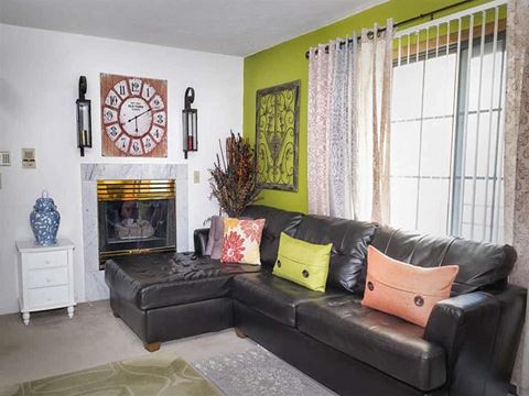 a living room with a black leather couch and a fireplace