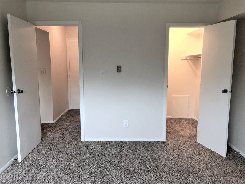 a bedroom with three doors and a carpeted floor