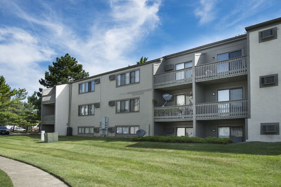the exterior of an apartment building with balconies and a lawn