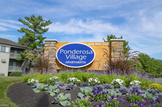 a sign for ponderosa village apartments in front of flowers
