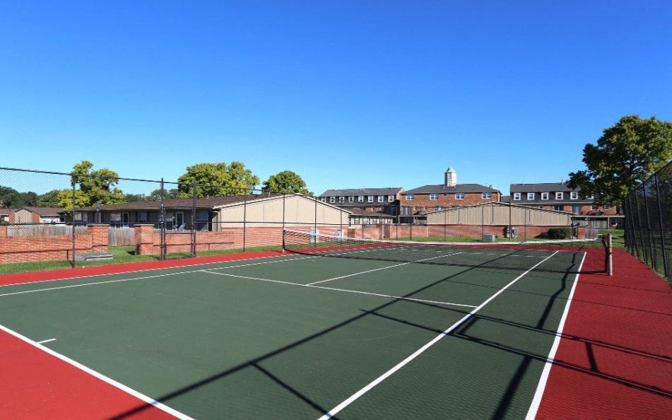 Tennis court with buildings in the background.
