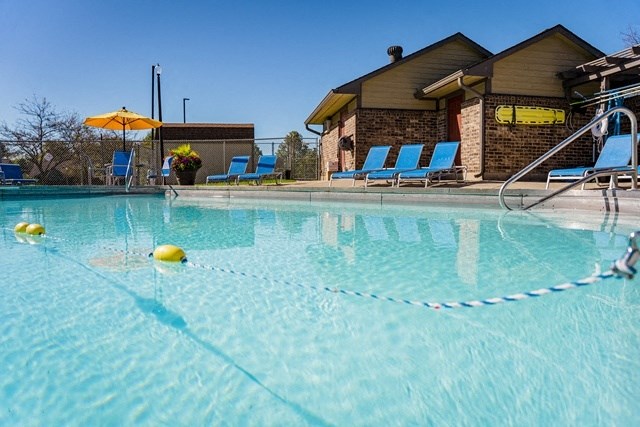 a swimming pool with blue lounge chairs and a resort style building