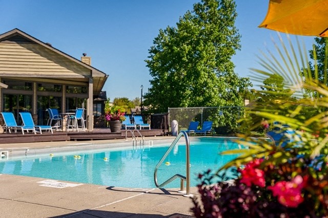 a swimming pool with blue chairs and a building in the background