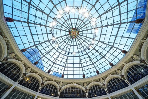 The image shows a beautiful glass dome ceiling with lights and arches.
