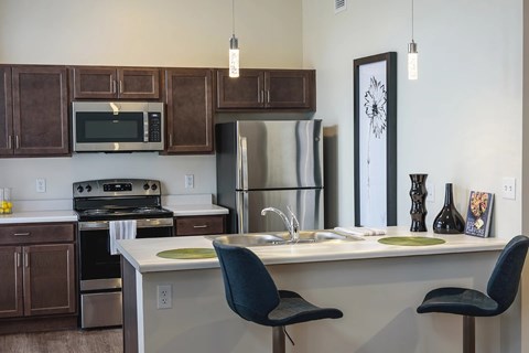 A kitchen with a white counter top and a black chair.