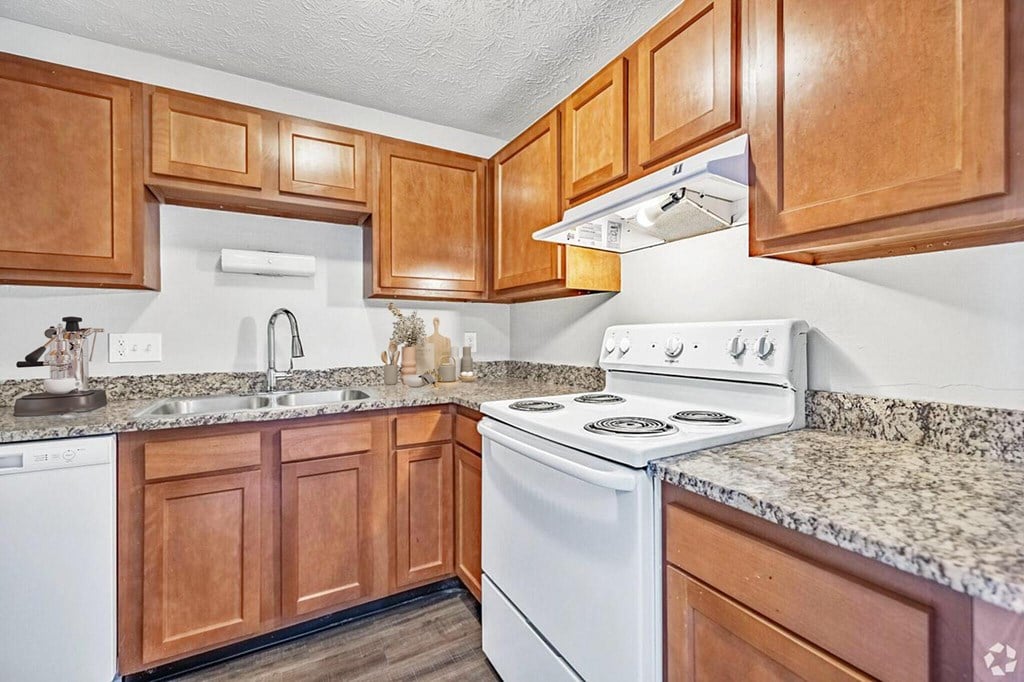 A kitchen with a white stove and wooden cabinets.