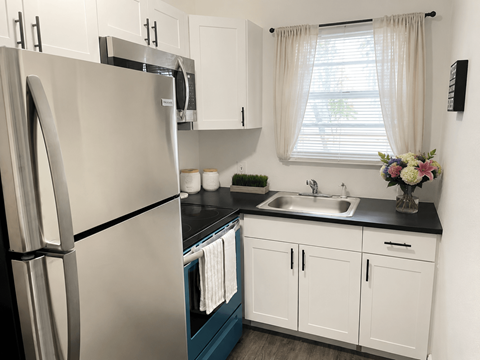 A kitchen with a stainless steel refrigerator and white cabinets.
