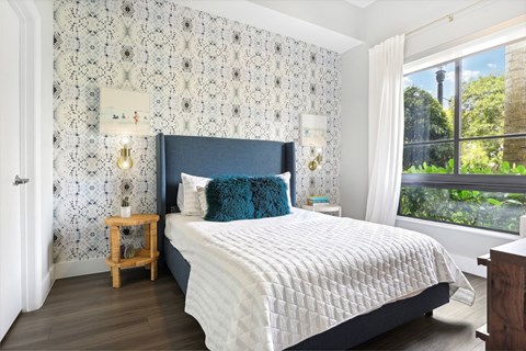 A bedroom with a large bed and a window overlooking a garden.