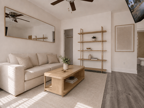 A living room with a white couch, a wooden coffee table, and a mirror on the wall.