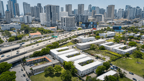 A cityscape with a mix of modern and older buildings, a highway, and greenery.