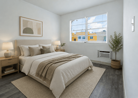 A bedroom with a large bed and a small tree.