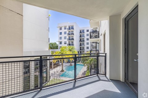 A balcony with a pool and a building in the background.
