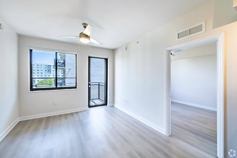 A spacious room with a ceiling fan and a view of the city.