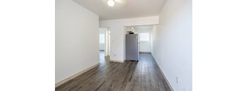 A room with a grey fridge and wooden floors.