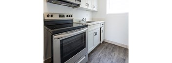 A modern kitchen with a stainless steel oven and white cabinets.