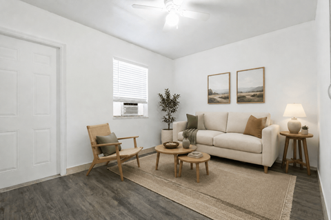 A living room with a white couch, a chair, a small table, and a plant.