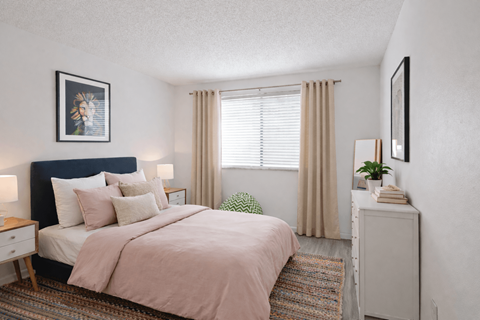 A bedroom with a bed, nightstand, and a window with curtains.