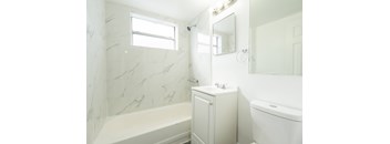 A white bathroom with a tub, sink, and mirror.