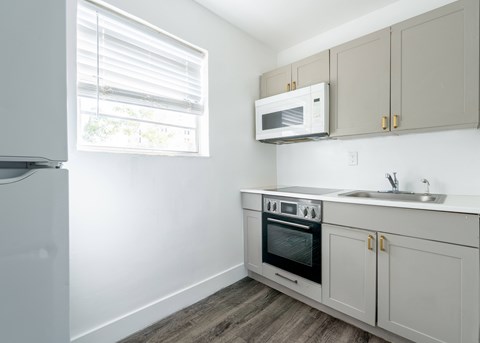 A kitchen with a white refrigerator, a microwave, a sink, and a stove.