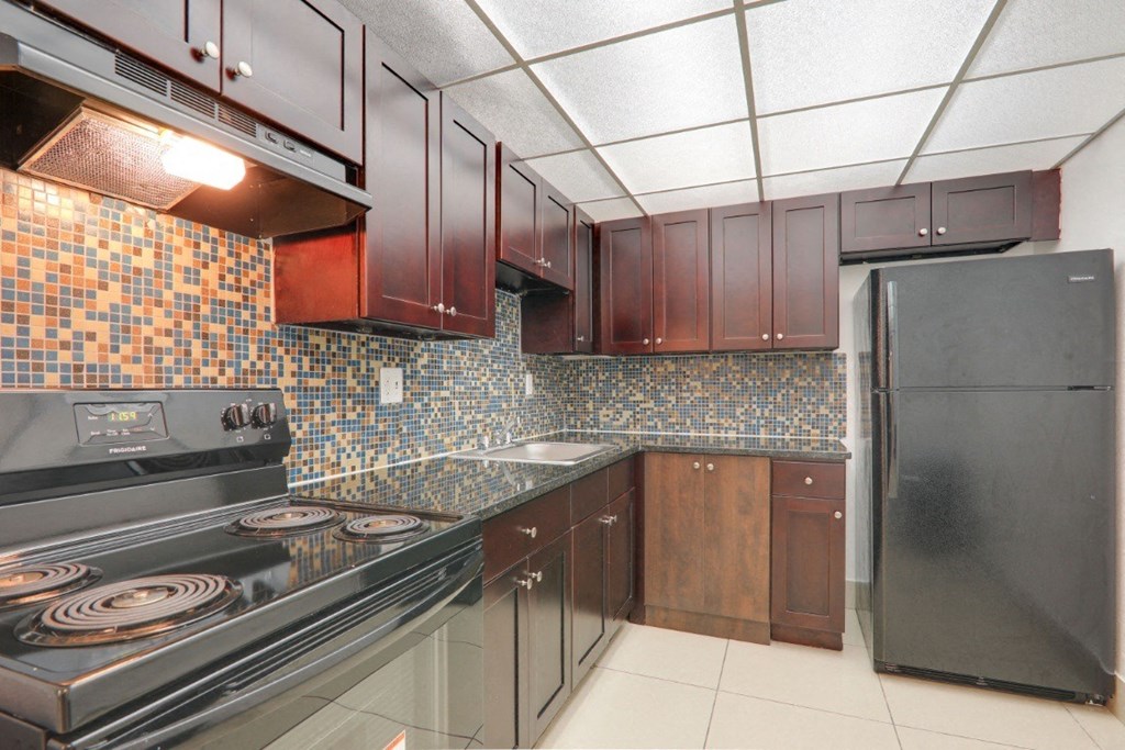 A kitchen with a black stove top oven and a black refrigerator.