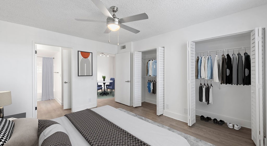 A bedroom with a bed, a chair, a wardrobe, and a ceiling fan.