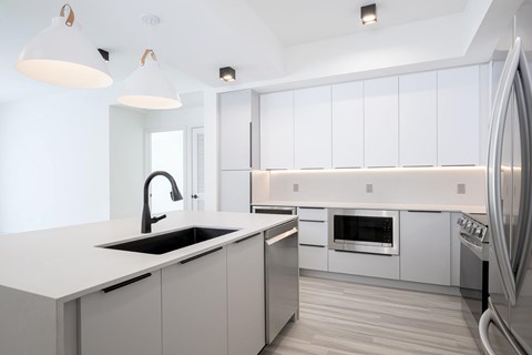 A modern kitchen with a white countertop and stainless steel appliances.