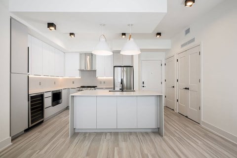A modern kitchen with a white cabinetry and a wooden floor.