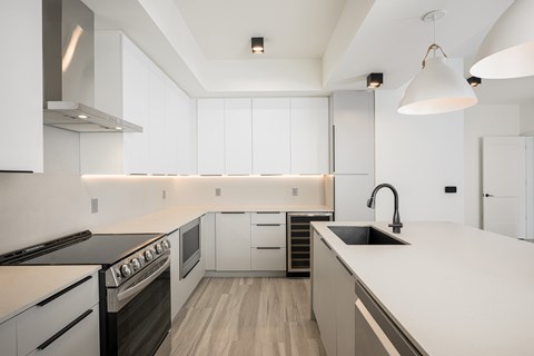 A modern kitchen with white cabinets and a black stove top oven.