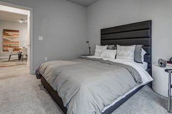 A bedroom with a large bed and a woven wall hanging.