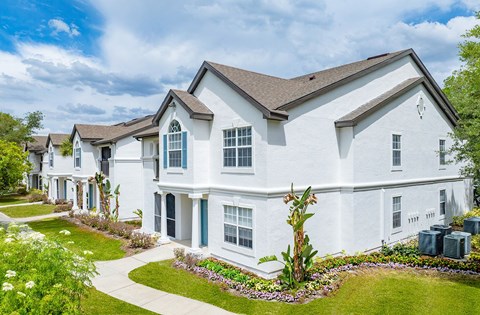 A white house with a brown roof and a green lawn in front.